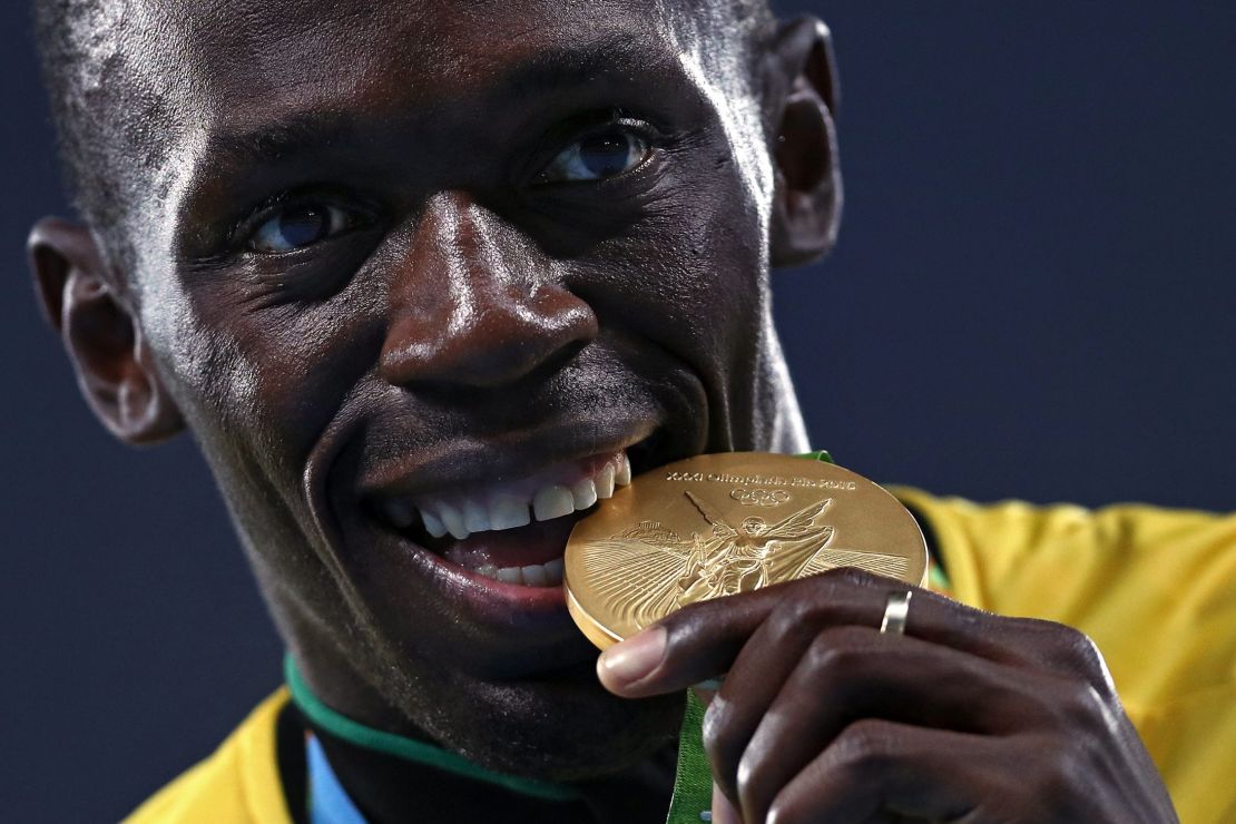 Bolt bites his gold medal after the 4x100 meter relay at the Rio 2016 Olympics.