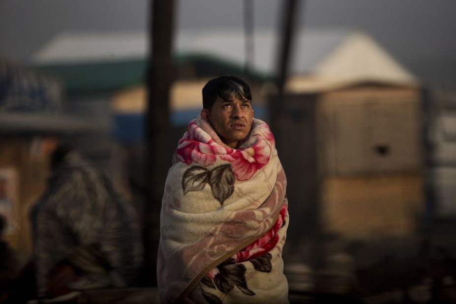 A man looks skyward as he stands beside the burned remnants of his tent in the Jungle on October 26.