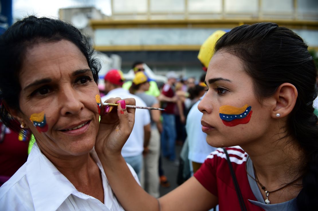 Women paint Venezuelan national flags on their faces during the march.