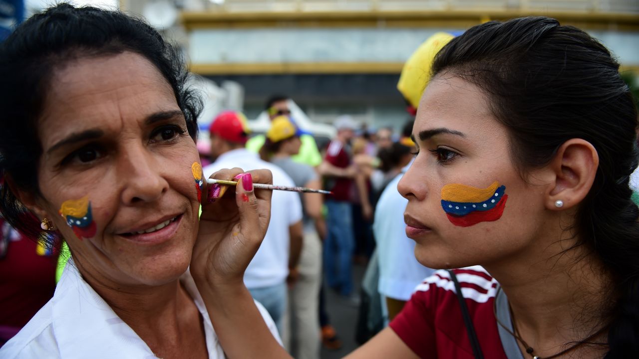 Women paint Venezuelan national flags on their faces during the march.