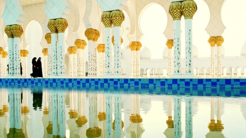 A 24-carat gold chandelier hangs in the main prayer hall of the Sheikh Zayed Grand Mosque and the walkways are lined by mirror pools amplifying its golden details.