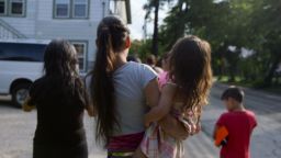 A mother and her children walk outside the refugee house they stayed in after being released from detention