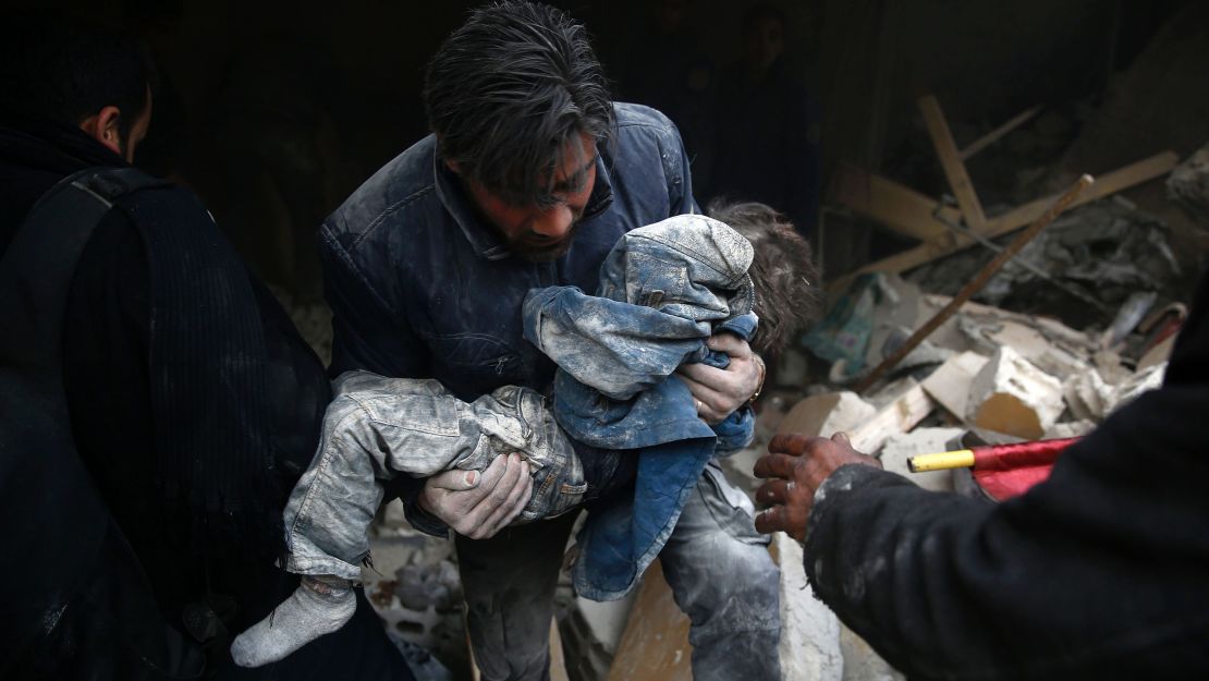 A Syrian man rescues a child after an airstrike in Douma in January.