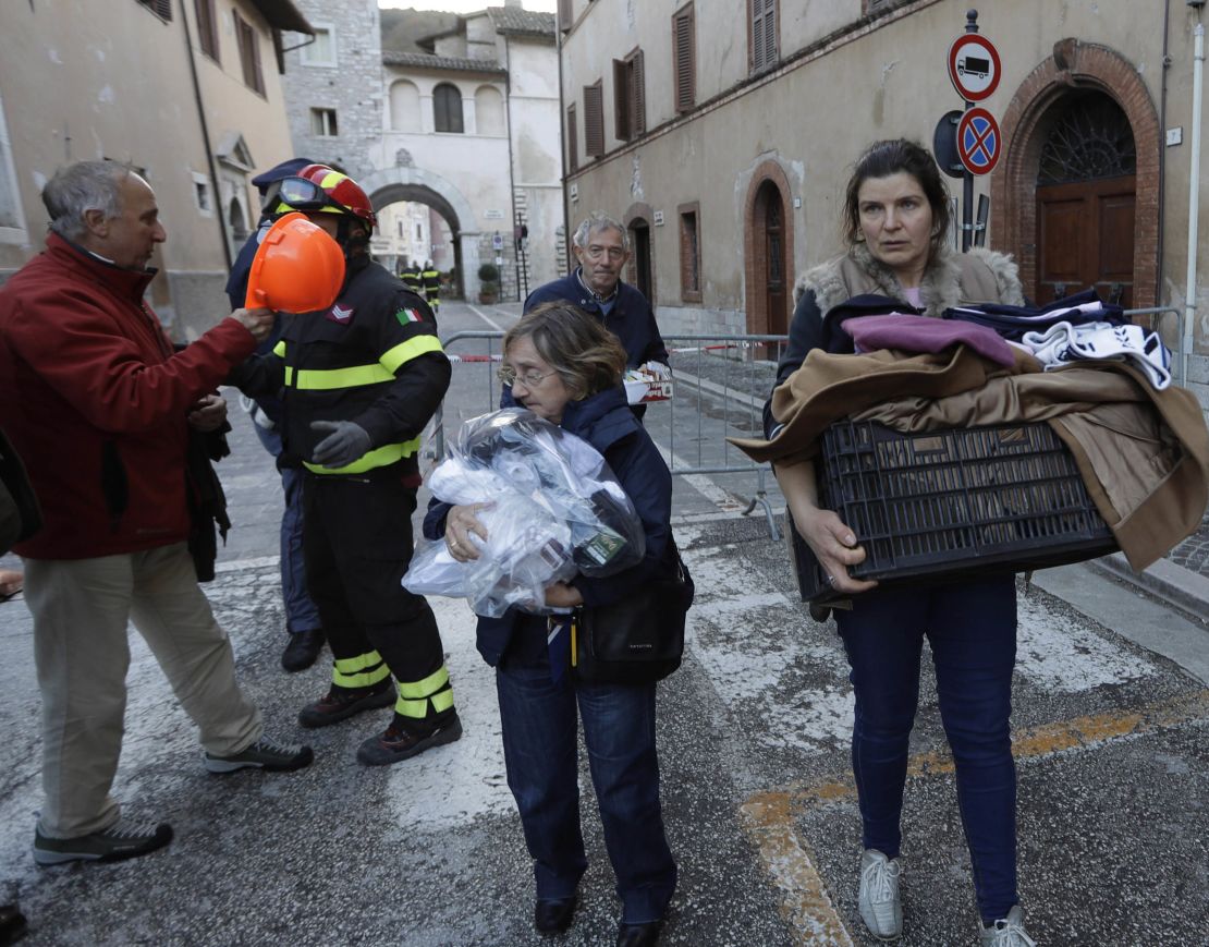 Residents carry some of their belongings through Visso. 