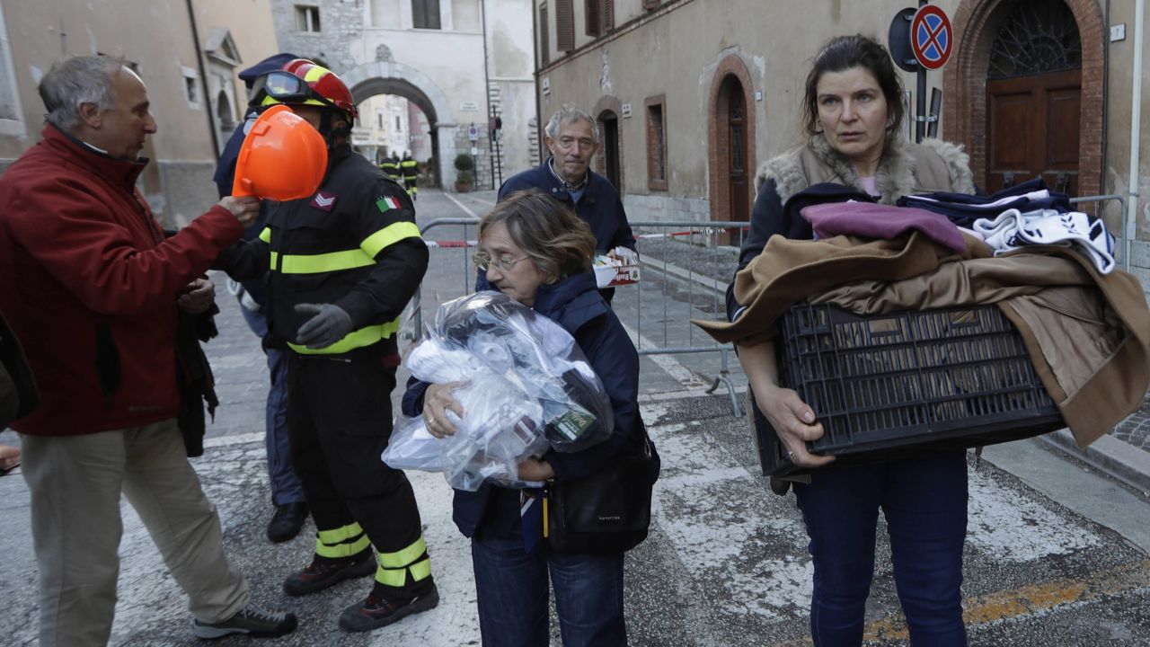 Residents carry some of their belongings through Visso.