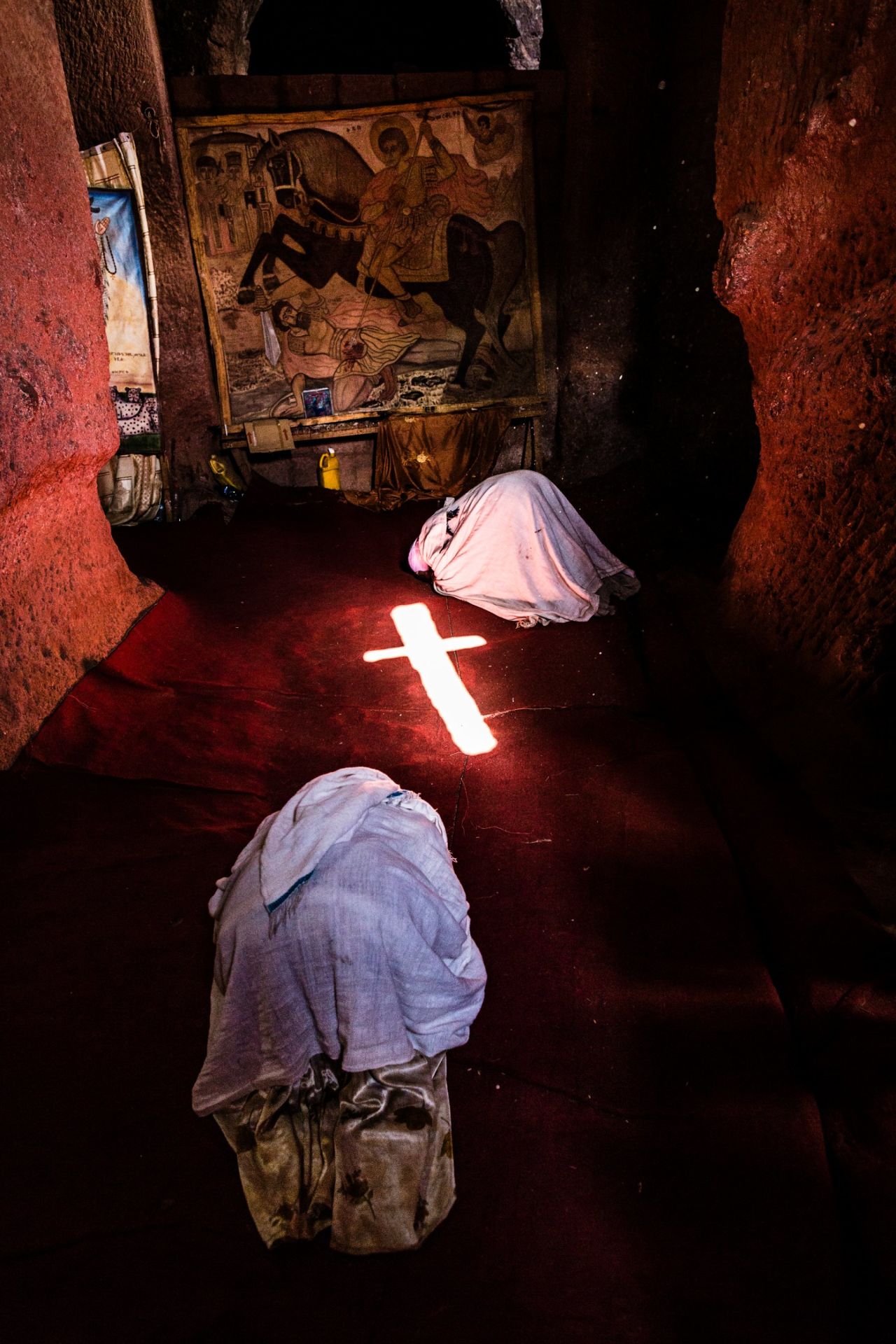 Pilgrims prostrate themselves in front of a tapestry of St George -- the patron saint of Ethiopia -- in one of Lalibela's ancient churches. Light shining in from the window projects a cross on to the floor, just one example of how these structures, hand-carved some 800 years ago, still work in harmony with their environment. 