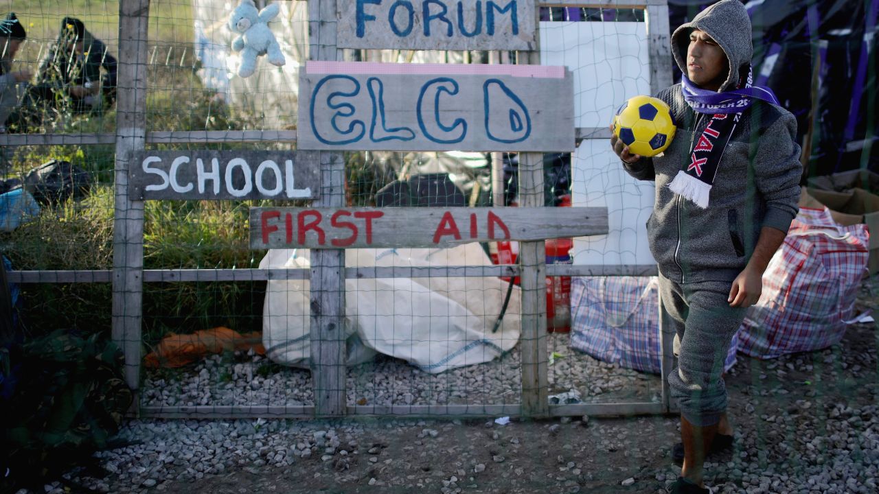 Migrants wait outside the Calais Jungle school house after they were allowed by police back inside to shelter for the night on October 28, 2016 in Calais, France.