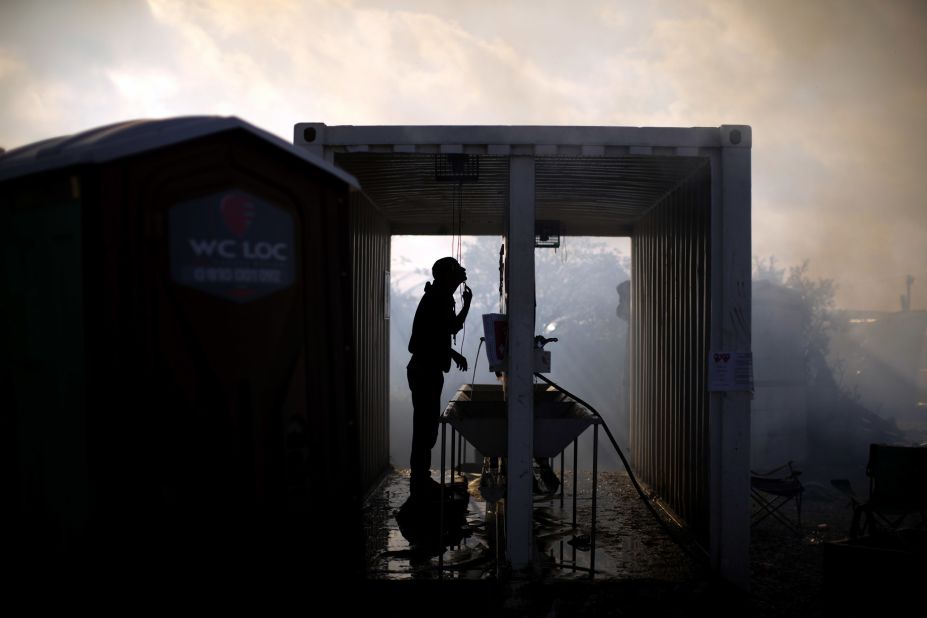 A migrant shaves while cleaning crews continue demolition of the Jungle on October 27