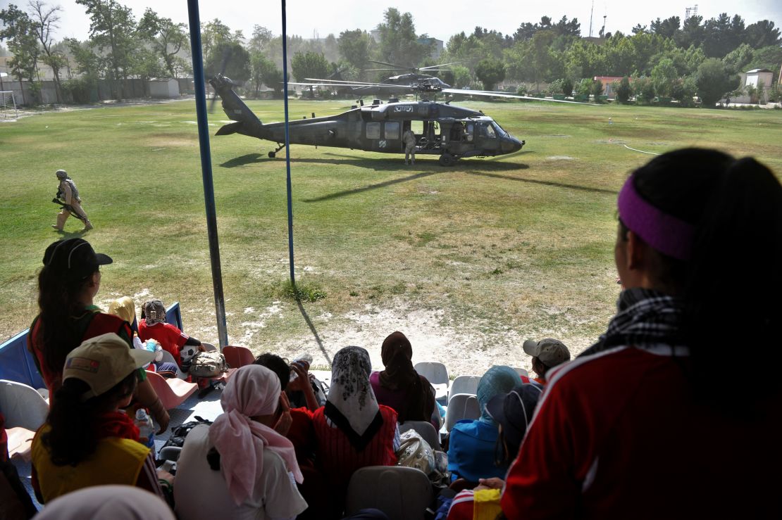  Afghanistan's women's national football team members take a break from training as a US Black Hawk helicopter lands.