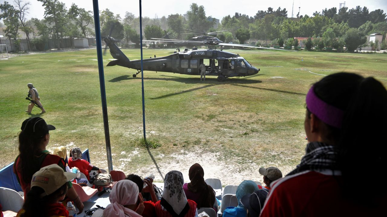  Afghanistan's women's national football team members take a break from training as a US Black Hawk helicopter lands.