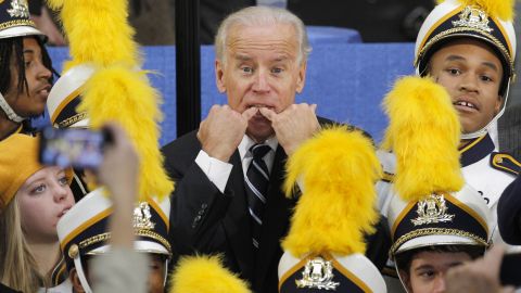 Biden whistles to get someone's attention as he stands with a high school marching band in Euclid, Ohio, in November 2011.