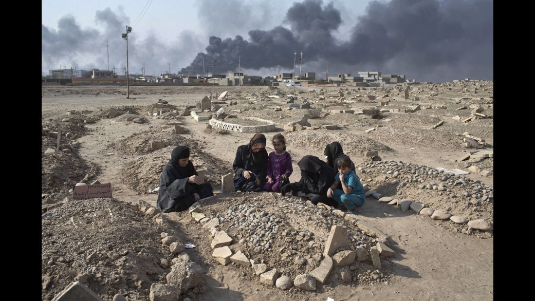 Women and children grieve over the grave of a family member at a Qayyara cemetery damaged by ISIS on October 27.