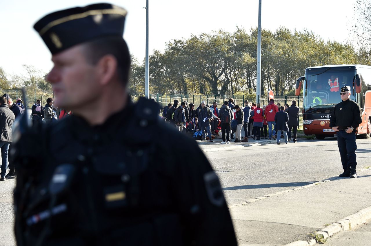 French authorities stand by as migrant minors board a bus to relocation centers on October 28. Authorities began work on Monday to clear the infamous migrant camp known as the Calais "Jungle" in northern France.