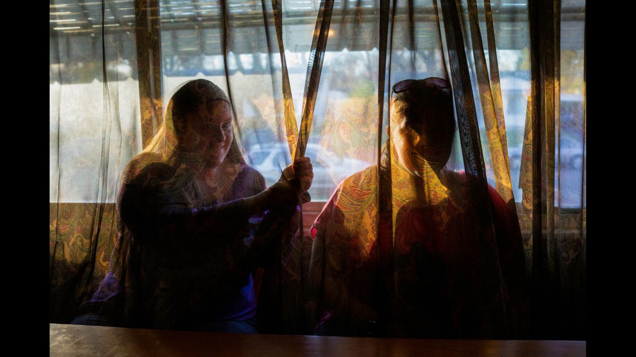 The twins are seen behind a living-room curtain in 2015. 