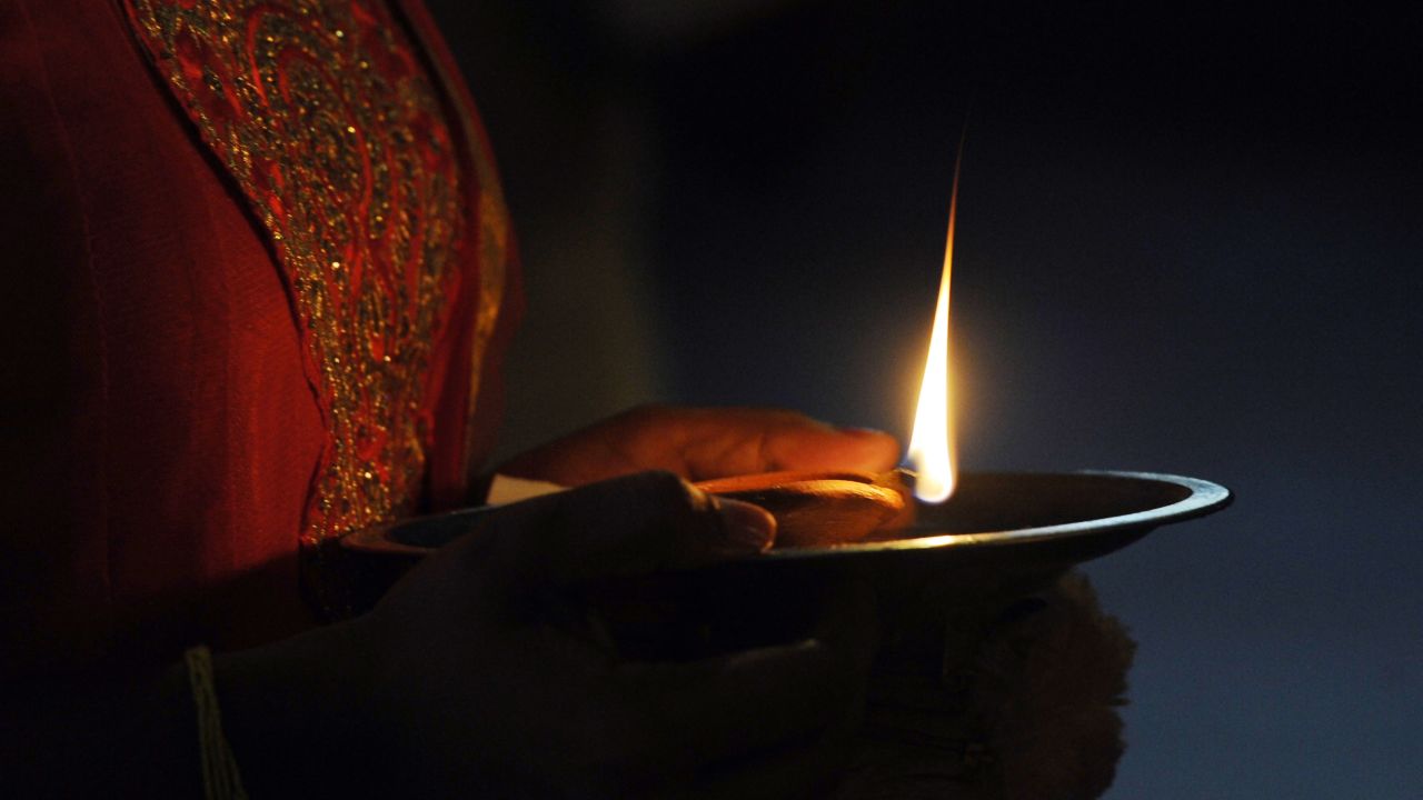 A woman holds an oil lamp while offering prayers in Colombo, Sri Lanka, on October 29.