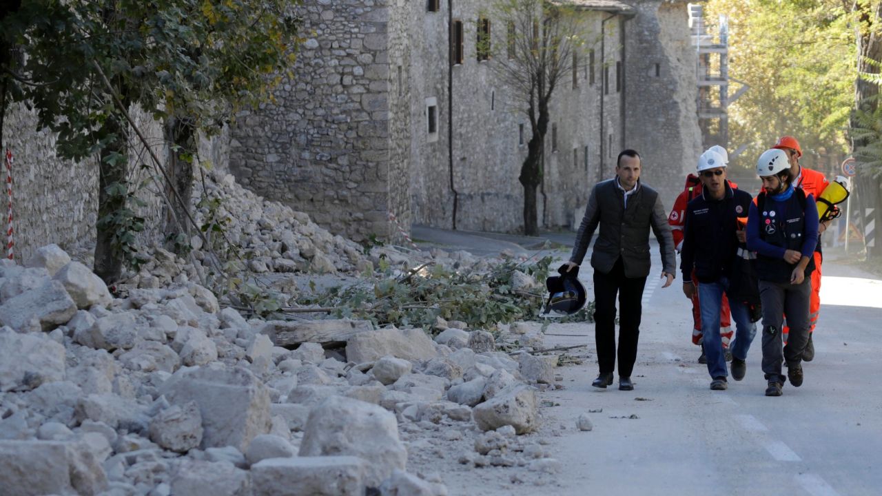 Italian civil protection staff pass a collapsed wall Sunday in Norcia after the quake jolted central Italy.