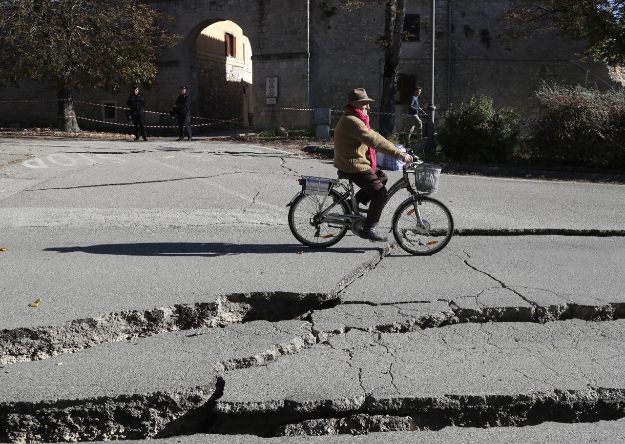A man rides a bicycle past cracks in a road in Norcia on October 30. The quake struck 6 kilometers (3.7 miles) north of Norcia, the US Geological Survey reported.