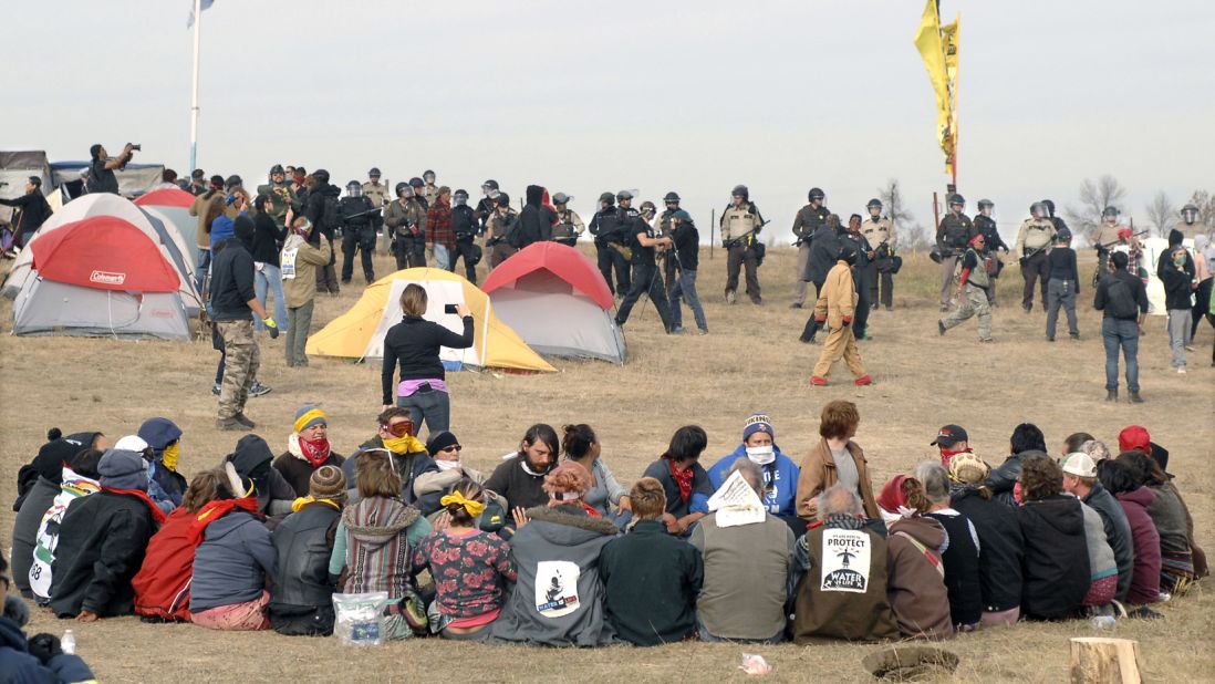 Pipeline protesters sit in a prayer circle as a line of law enforcement officers make their way across the camp to relocate the protesters a few miles south on Thursday, October 27. Protesters had camped on private property.