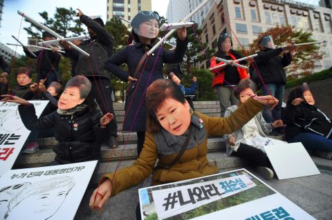 Protesters wearing masks of South Korean President Park Geun-Hye and her confidante Choi Soon-Sil perform before a candlelit rally in central Seoul on Saturday.