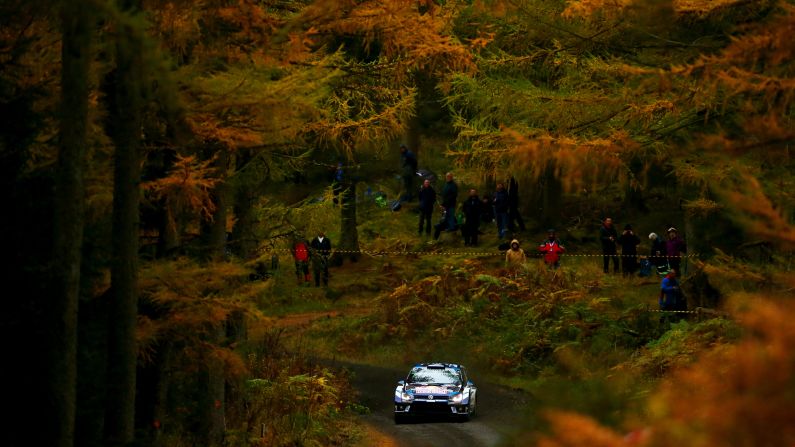 The rally car of Sebastien Ogier and Julien Ingrassia speeds through a forest in Mynydd Hiraethog, Wales, on Thursday, October 27.
