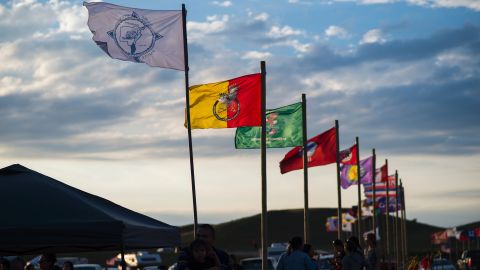Flags of Native American tribes from across the US and Canada line the entrance of the camp.