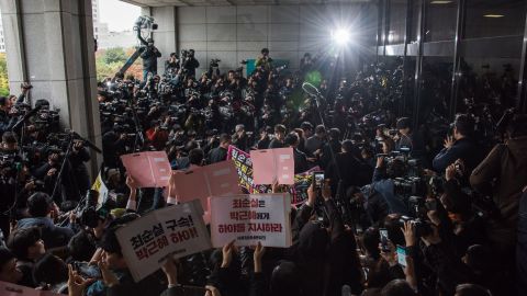 Reporters and protesters surround Choi Soon-sil as she enters the prosecutor's office Monday in Seoul.
