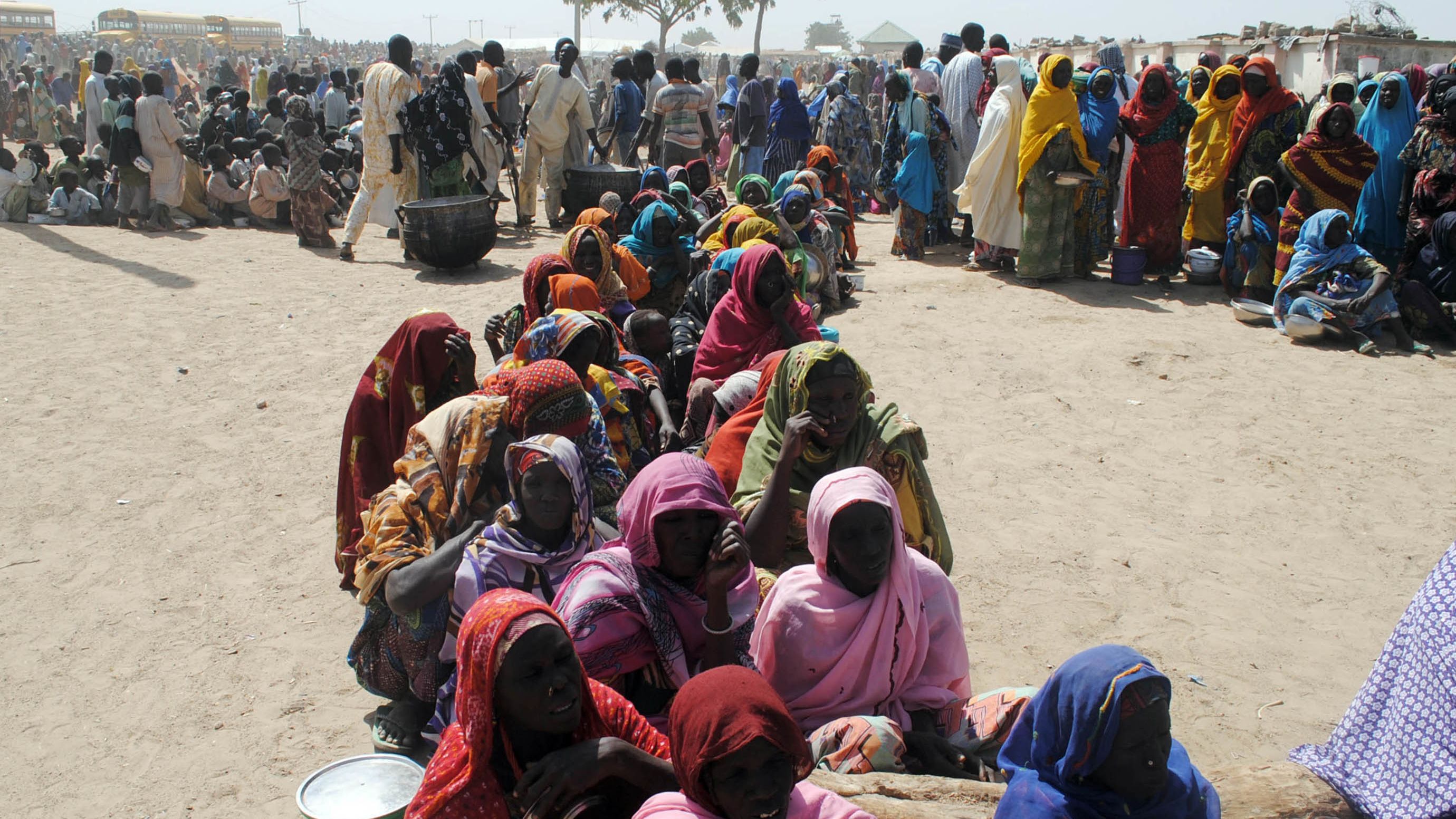 Women and children sit among displaced people waiting to be served food at Dikwa Camp, in Borno State, Nigeria, in January, 2016. 