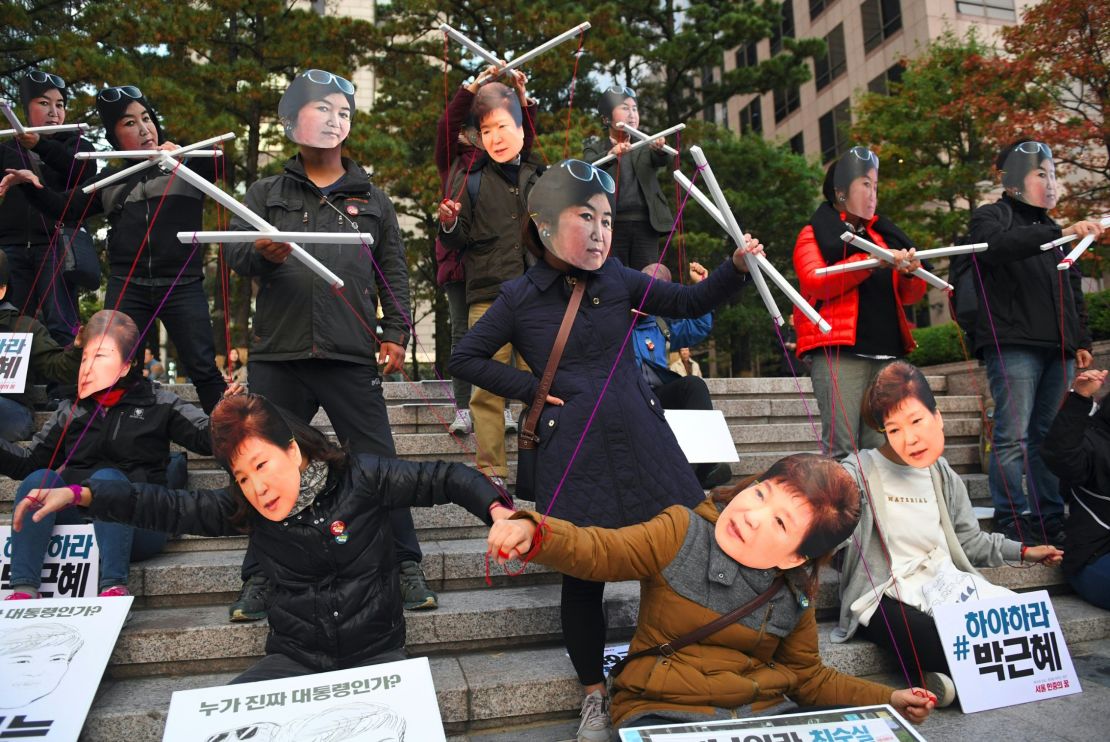 Protesters wear masks of South Korean President Park Geun-hye and Choi Soon-sil.