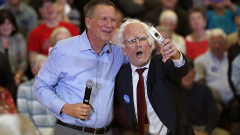Ohio Gov. John Kasich, one of the Republican presidential candidates, poses with a Sanders impersonator at the end of a town-hall meeting in Palatine, Illinois, on March 9, 2016. 