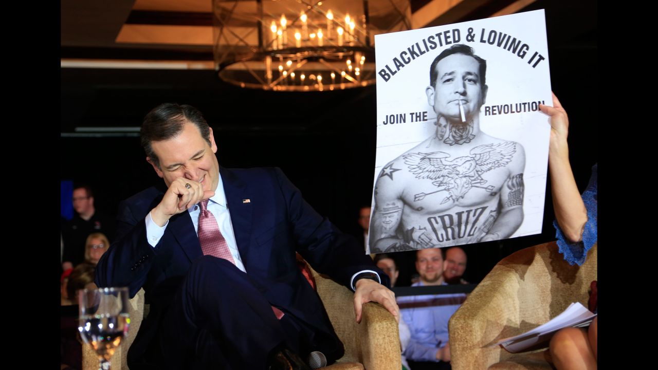 Cruz laughs at a poster while speaking a town-hall event in Madison, Wisconsin, on March 30, 2016.