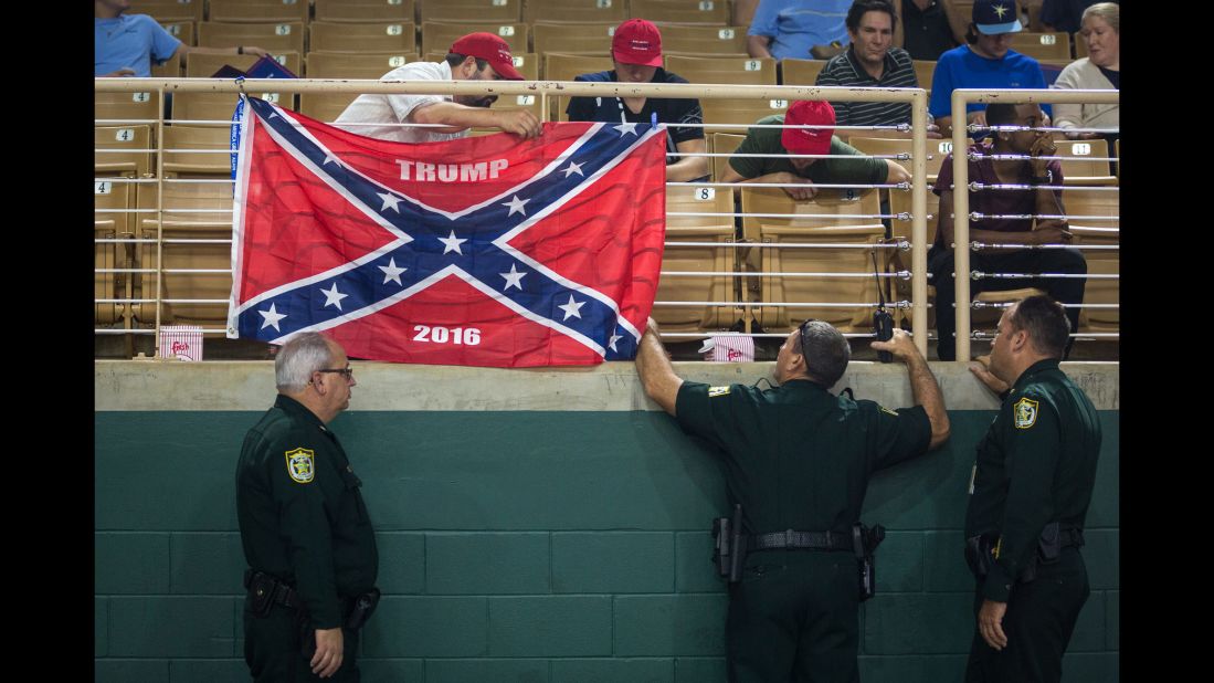 Law enforcement officers make Trump supporters remove a Confederate flag display at a Trump rally in Kissimmee, Florida, on August 11, 2016.