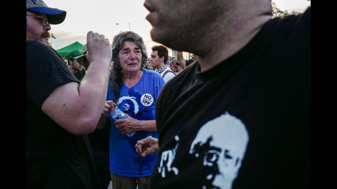 A woman reacts after allegedly being pepper-sprayed as a group of protesters tried to push through the police lines and enter the Democratic National Convention.