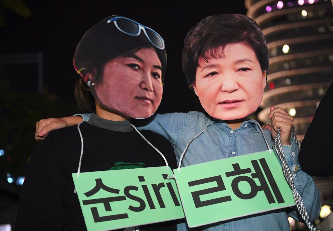 Protesters wear masks depicting Choi Soon-sil and Park Geun-hye. 