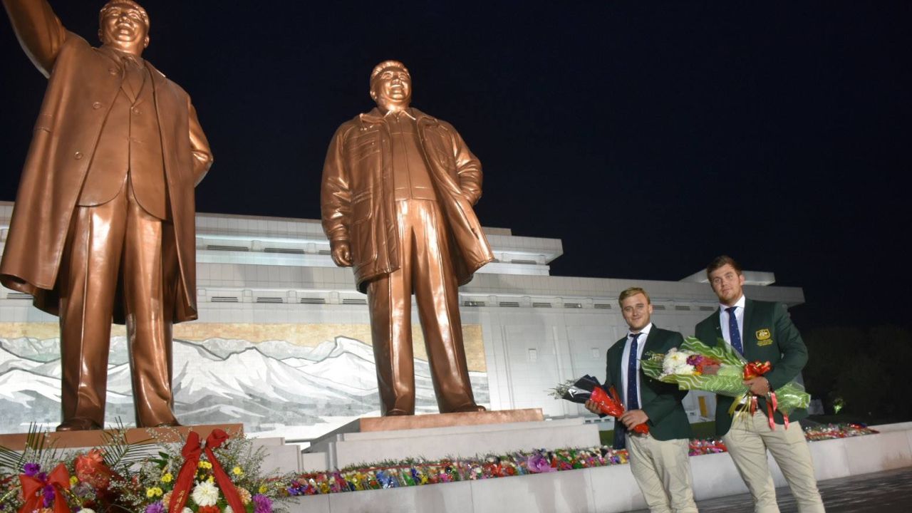 Evan Shay, left, and Morgan Ruig, right, stand beside statues of former North Korean leaders following their prank turn in a golf tournament there.