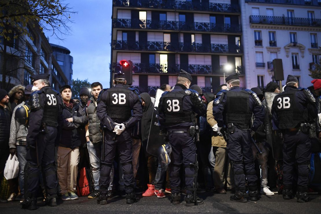 A line of police restrain migrants during Friday morning's evacuation of the camp in Paris. 