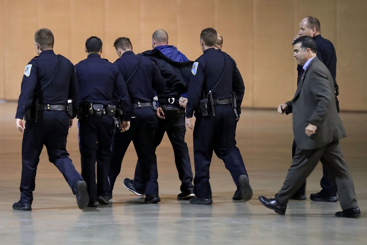 Police officers and Secret Service agents take a man away in handcuffs after the Reno disruption.
