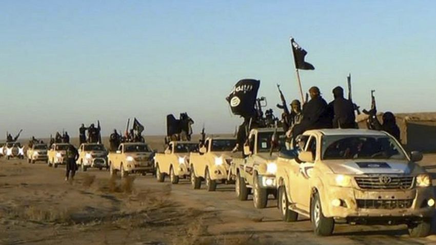 FILE - In this undated file photo released by a militant website, which has been verified and is consistent with other AP reporting, militants of the Islamic State group hold up their weapons and wave flags on their vehicles in a convoy on a road leading to Iraq, while riding in Raqqa, Syria. Simultaneous attacks on the Islamic State-held city of Mosul in Iraq and Raqqa, the de facto IS capital across the border in eastern Syria, would make military sense: They would make it harder for the extremists to move reinforcements and deny them a safe haven. (Militant website via AP, File)