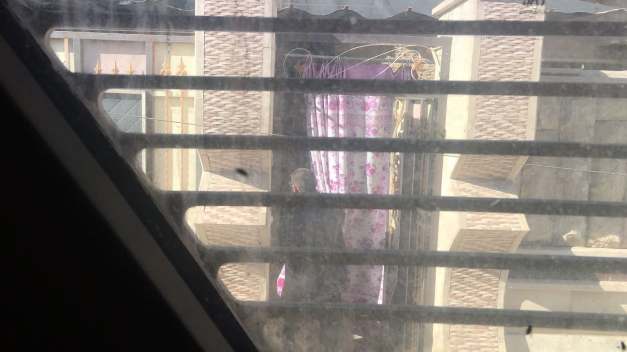 The man who hung the white rag on the pole walks back into his house after bringing out tea for the soldiers.