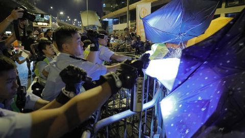 Protesters use umbrellas to block the pepper spray from police officers.