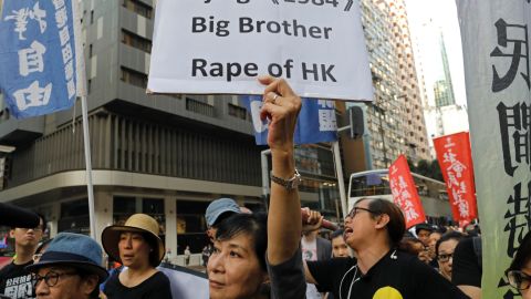A protester raises a placard as thousands of people march through a downtown street in Hong Kong, Sunday.