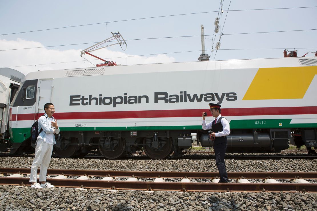 Chinese employees of the new railway which will link Addis Ababa to Djibouti take pictures in front of the Chinese-made Ethiopian trains in Addis Ababa on September 24, 2016.