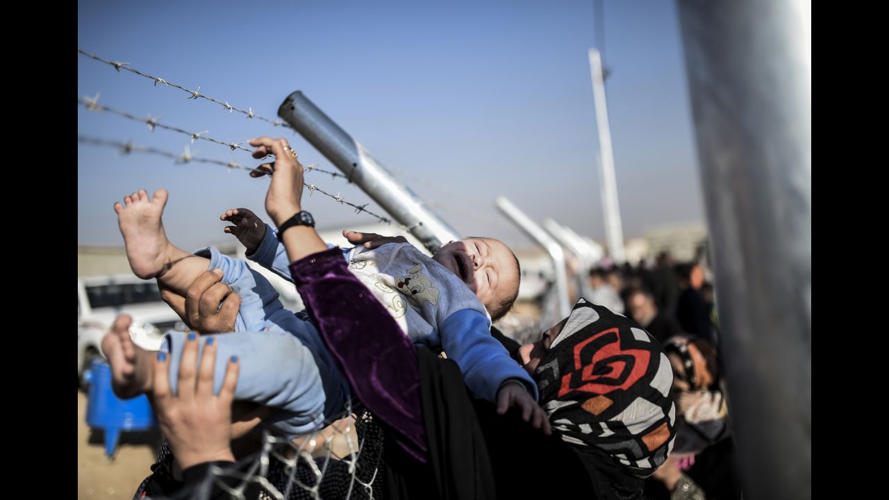 A baby is passed through a fence back to his mother at a refugee camp in the Khazir region on Saturday, November 5.