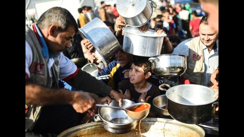 People line up to receive food at a refugee camp in the Khazir region on November 5. Thousands are taking refuge in camps set up for internally displaced people.