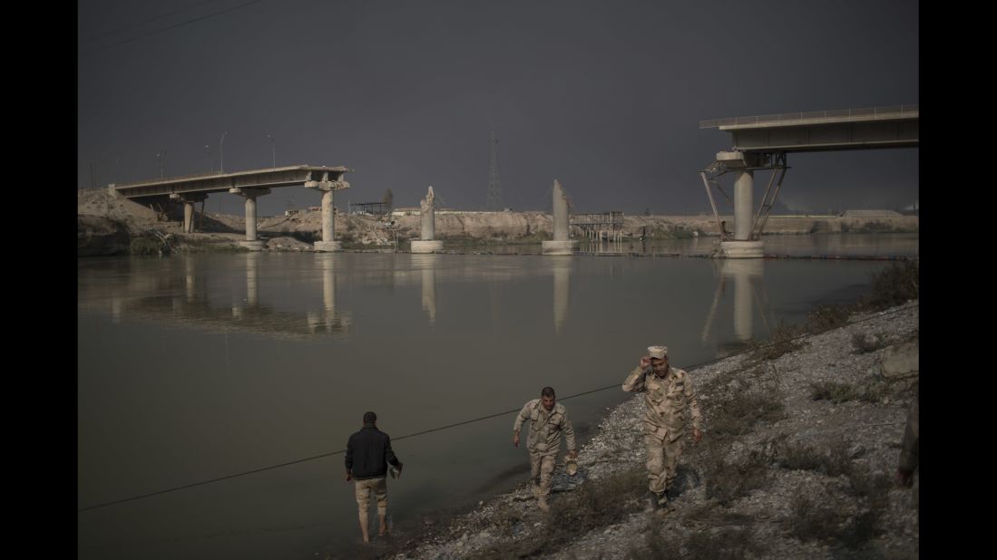 Iraqi soldiers pass near a bridge destroyed in an airstrike in Qayyara on November 5.