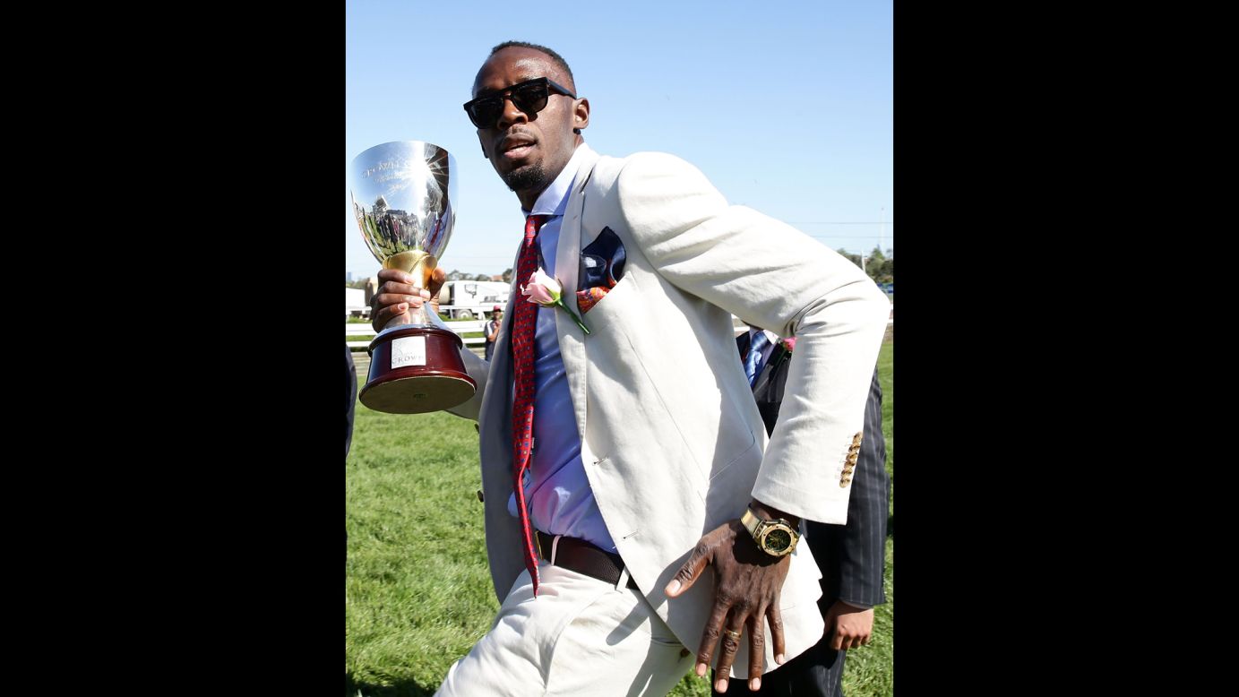 Usain Bolt, the world's fastest man, carries the Crown Oaks Trophy before handing it to the horse race winner in Melbourne on Thursday, November 3.