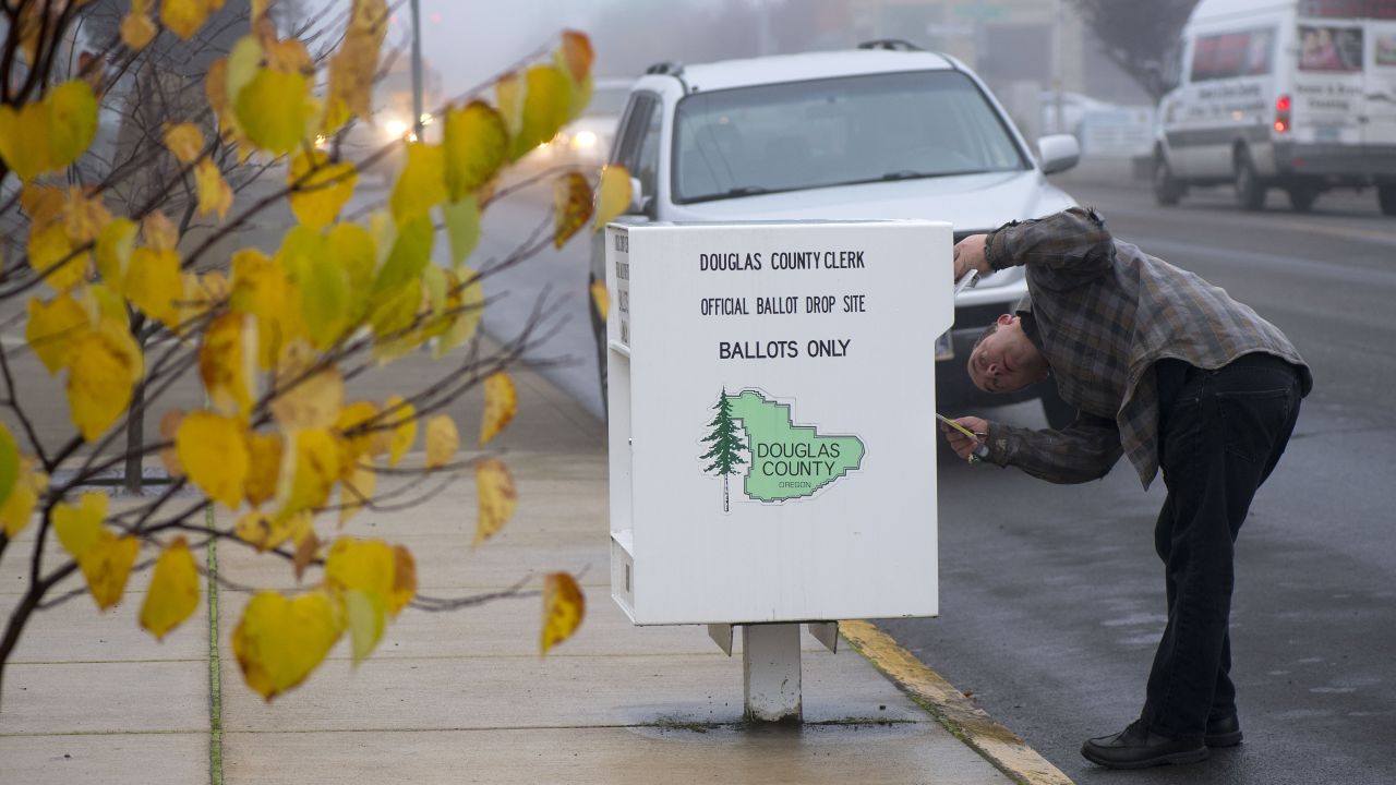 A voter drops his ballot into a voting box in Sutherlin, Oregon.