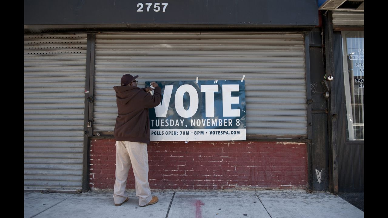 A man in Philadelphia hangs a sign reminding people to vote.