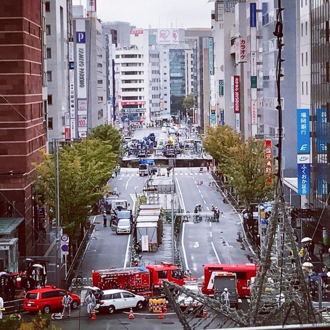 A giant sinkhole has opened up in Fukuoka, Japan, swallowing huge sections of road including traffic lights, near to underground work to extend a subway tunnel.  Will Barker was close to Hakata Station and captured this image, showing emergency vehicles blocking access to the road.  He told CNN: The hole was interesting, so I went to investigate.