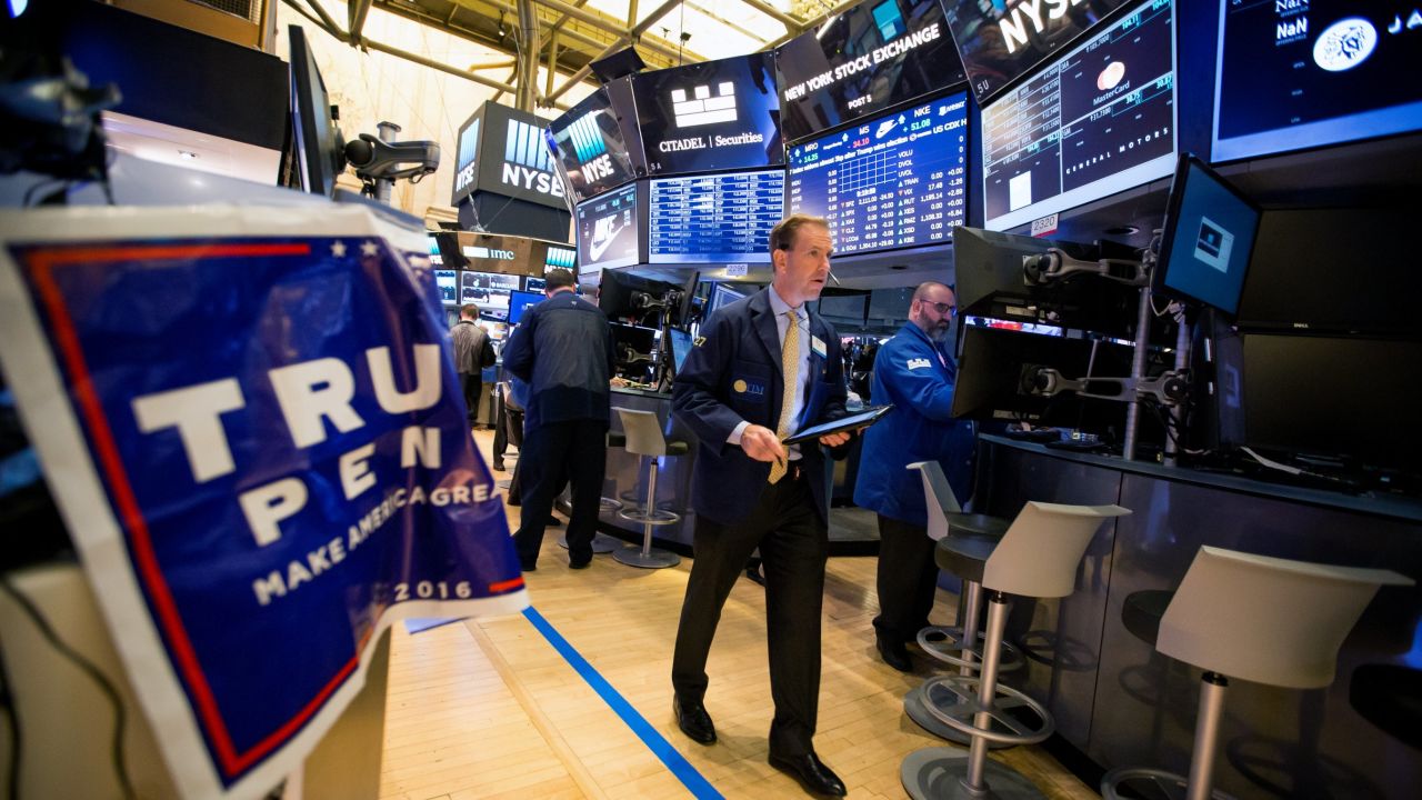 A trader walks past a campaign sign for U.S. President-elect Donald Trump and U.S. Vice President-elect Mike Pence on the floor of the New York Stock Exchange (NYSE) in New York, U.S., on Wednesday, Nov. 9, 2016.