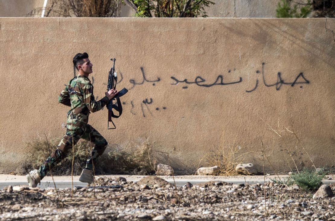 A Peshmerga fighter runs to take position in the town of Bashiqa, near Mosul.